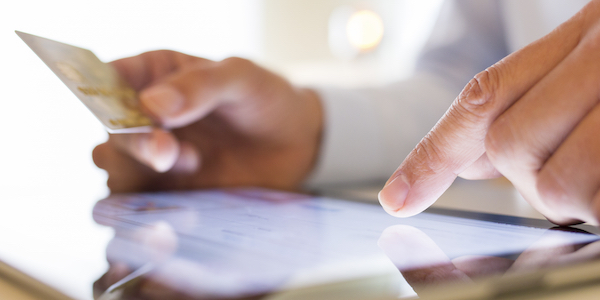 Man holding credit card and paying for item on tablet